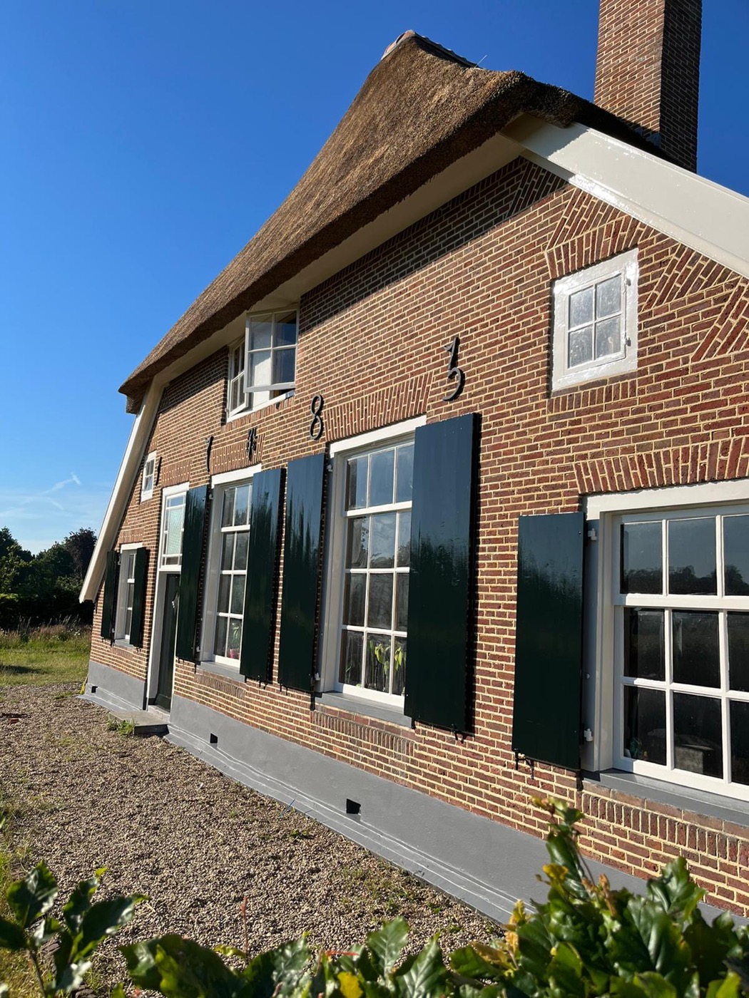 Monumentale boerderij met rieten dak en glanzend geschilderde luiken
